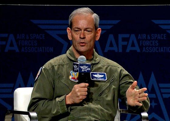 A man in a military uniform speaks from a chair.