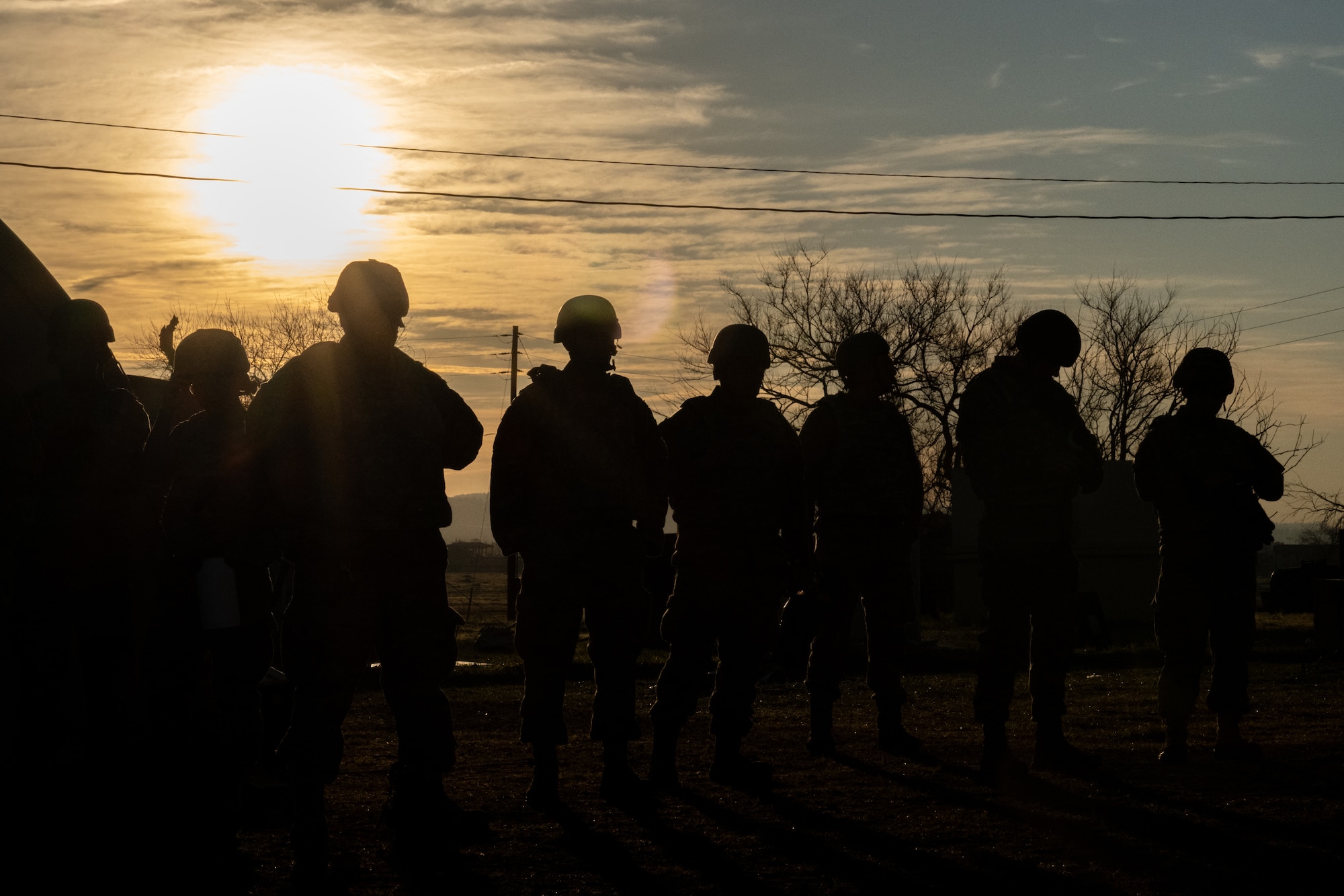 A silhouette of Airmen in front of a sunset