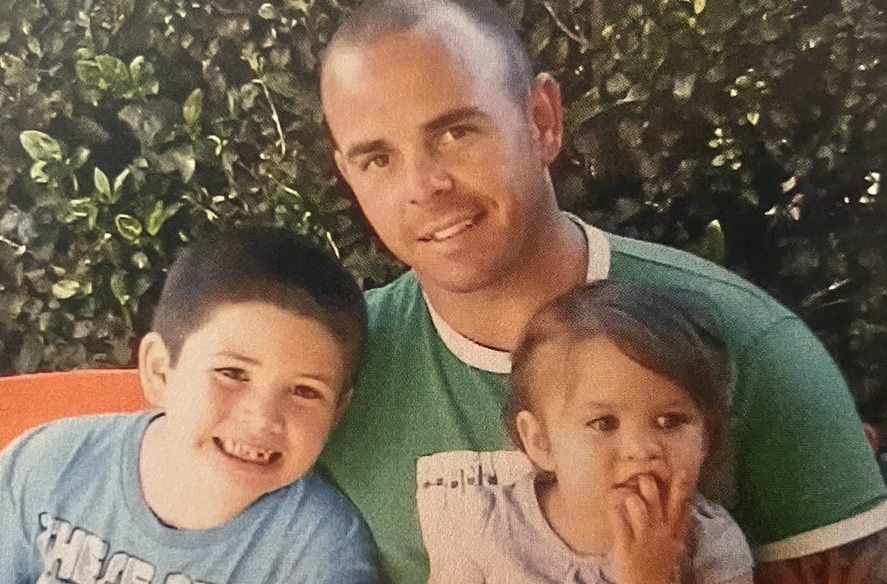A man poses with two small children.