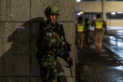An airman with a weapon taking cover by a wall