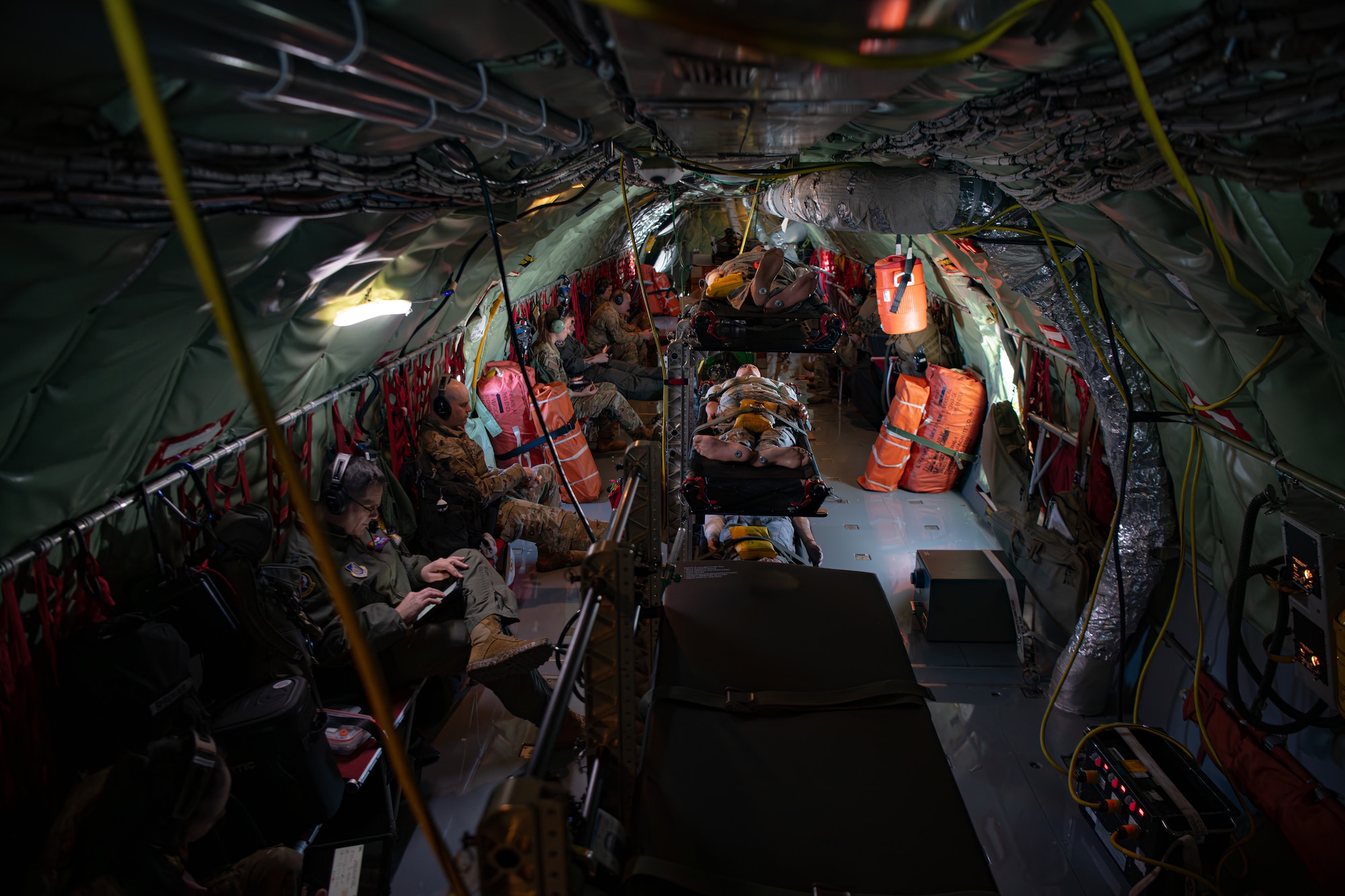 An interior shot of the fuselage of a KC-135 with medical members sitting in seats and training dummies in the center of the aircraft.