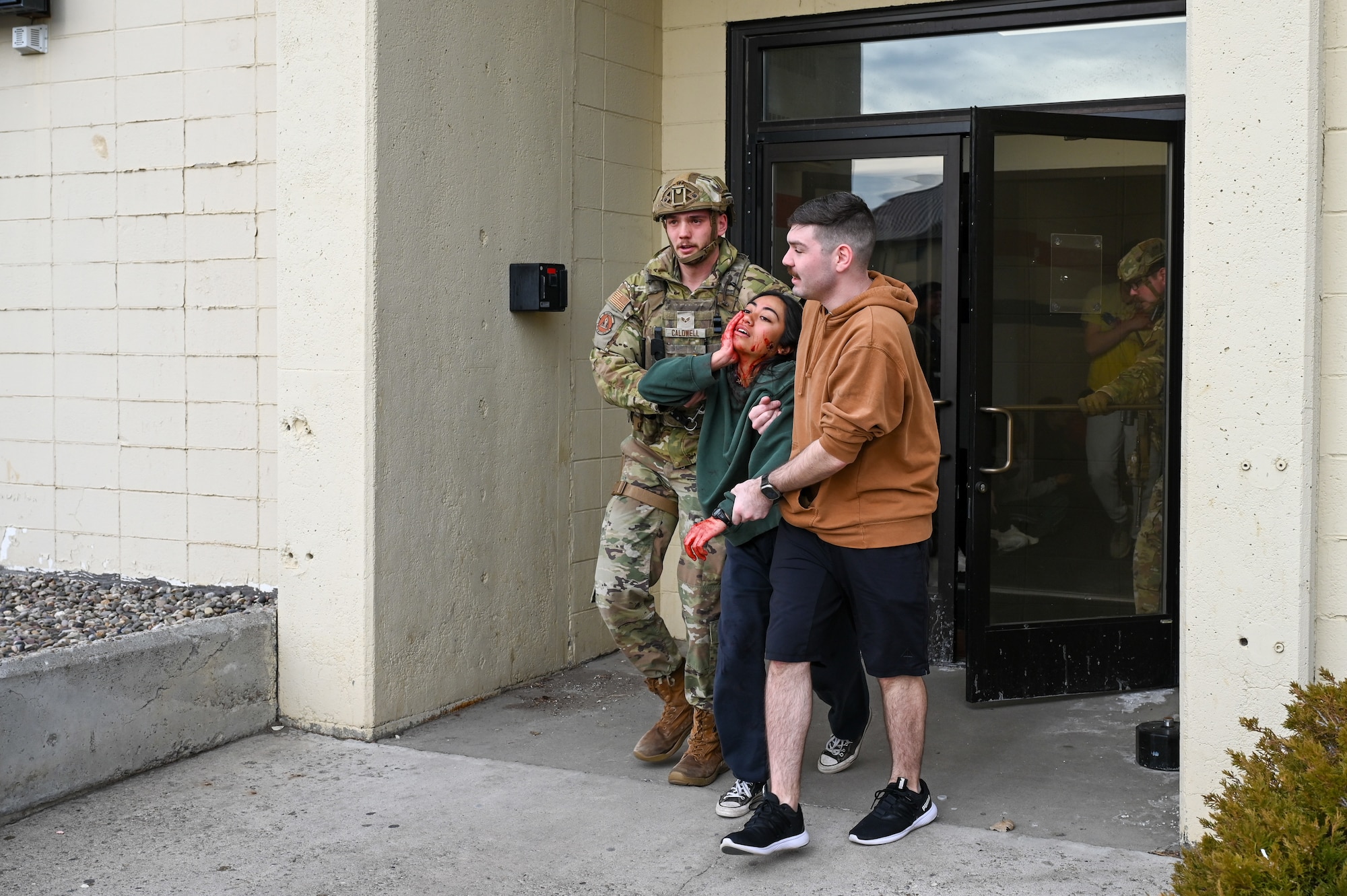 Uniformed personnel provide aid and security to simulated victims of a simulated active shooter.