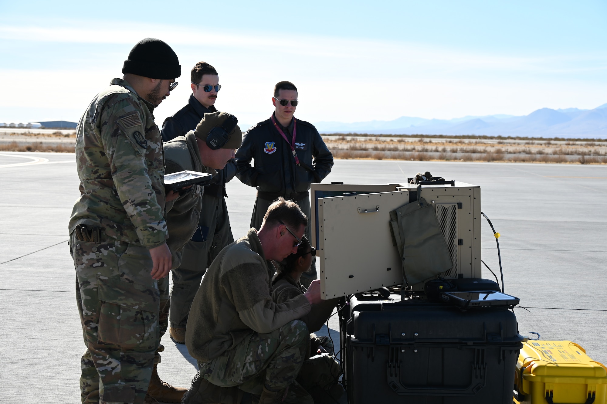 Men in military uniforms review data on screens.