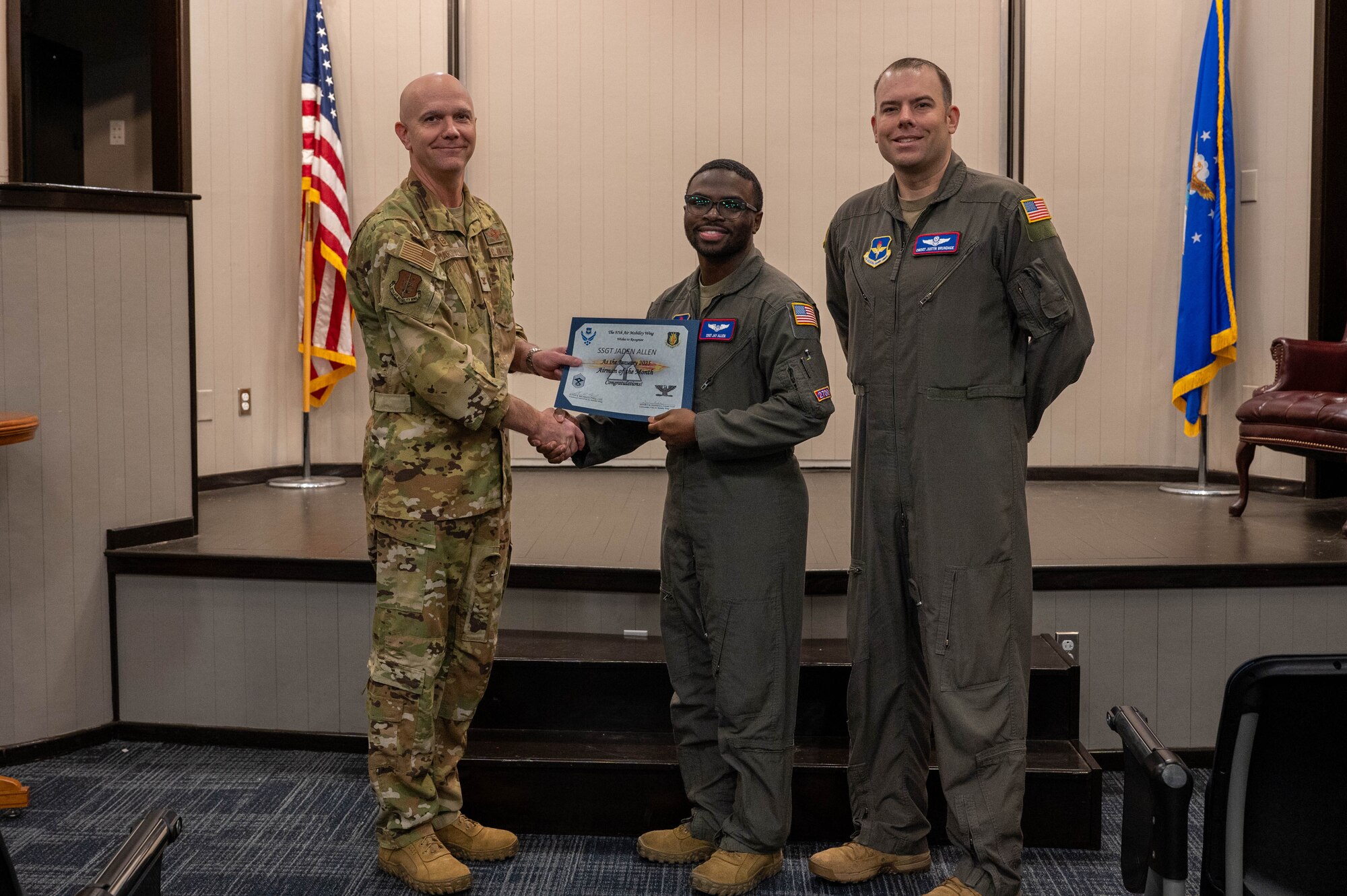 U.S. Air Force Col. Jeff Marshall, 97th Air Mobility Wing (AMW) commander, left, and Chief Master Sgt. Justin Brundage, 97th AMW command chief, right, awards Staff Sgt. Jaden Allen, 54th Air Refueling Squadron instructor boom operator, at Altus Air Force Base, Oklahoma, Feb. 27, 2025. Allen earned the award by striving for excellence in his job, maintaining a 4.0 grade point average while working towards his degree, and for his volunteer work with the wing resiliency team. (U.S. Air Force photo by Senior Airman Kari Degraffenreed)
