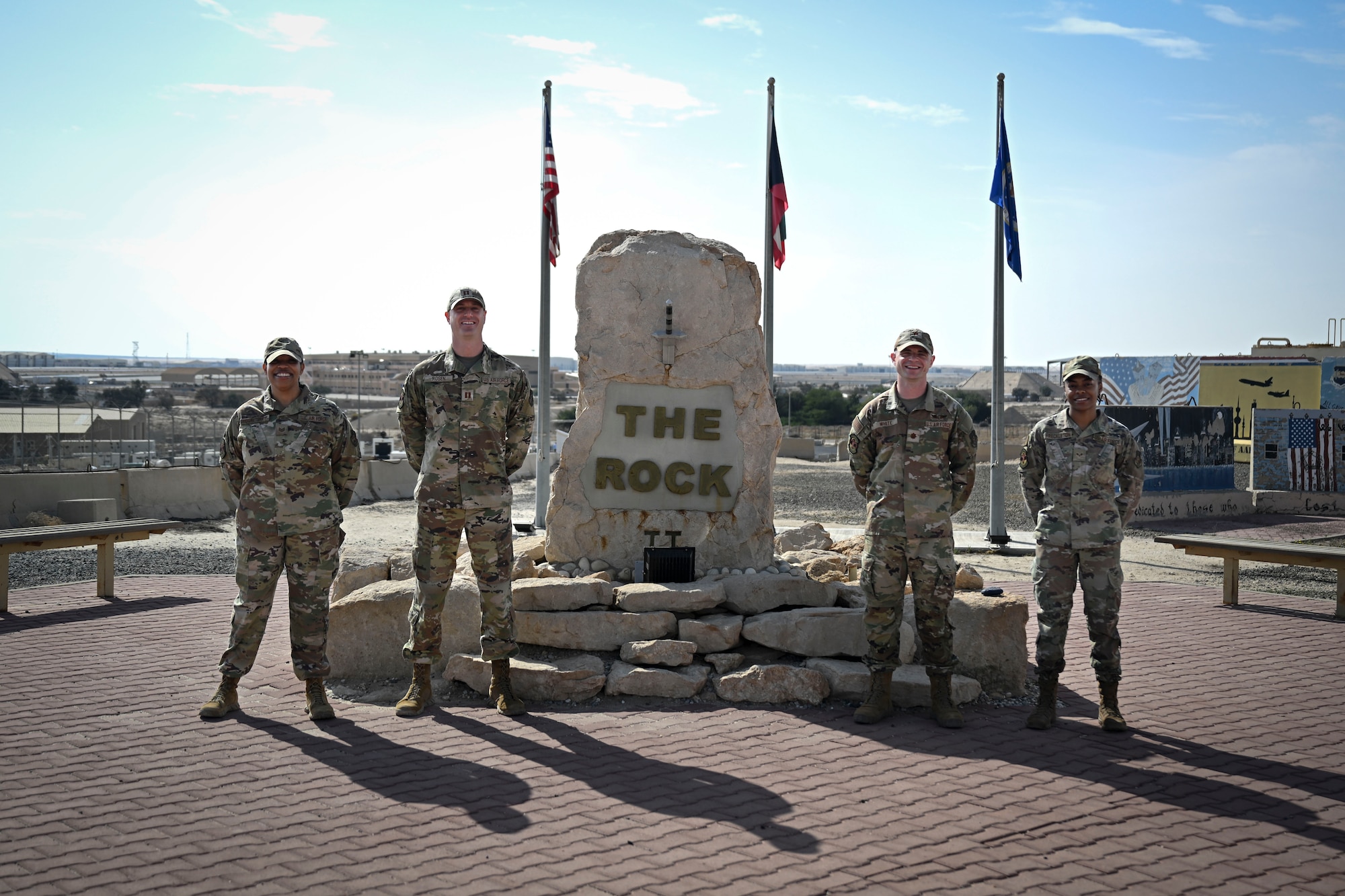 Four U.S. Air Force Airmen pose for a photo outside.