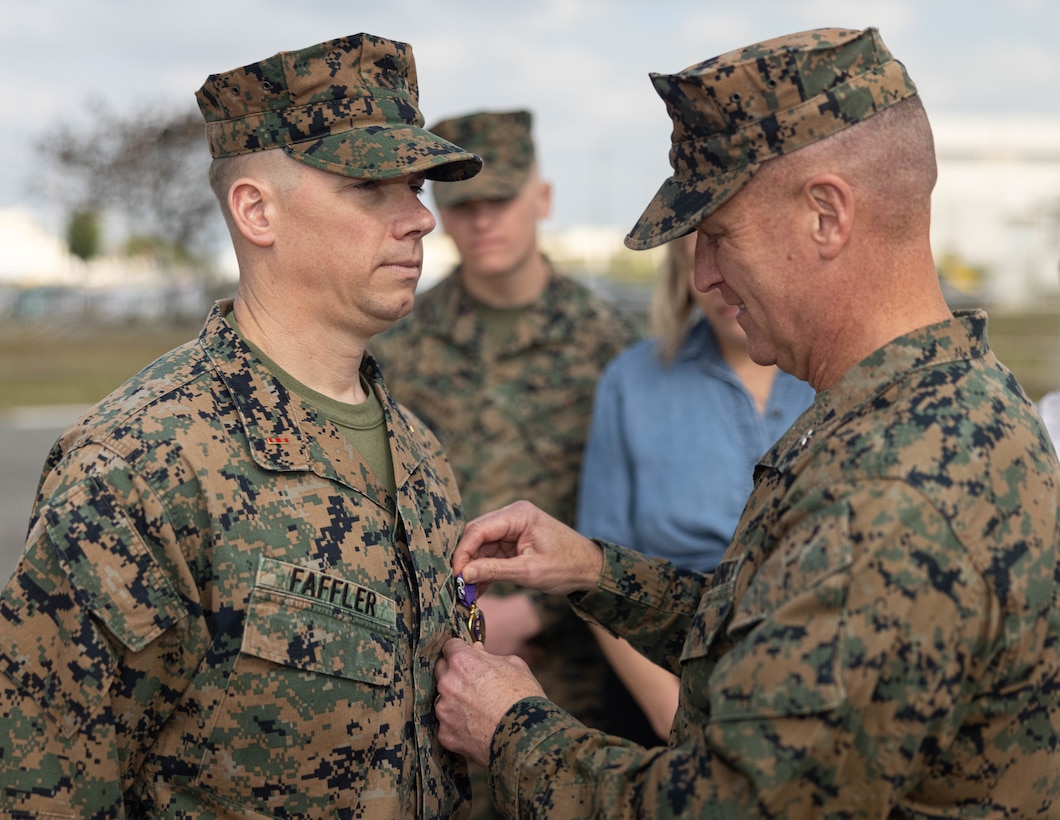 U.S. Marine Corps Brig. Gen. Kevin G. Collins, right, the commanding general of 3rd Marine Logistics Group (3rd MLG), presents a Purple Heart to Chief Warrant Officer 2 William Faffler, left, a visual information officer with 3rd MLG, during a Purple Heart ceremony on Camp Kinser, Okinawa, Japan, Jan. 6, 2025. Faffler received two Purple Hearts, both for wounds sustained during combat operations in support of Operation Enduring Freedom in Helmand Province, Afghanistan, May and October of 2010. (U.S. Marine Corps photo by Lance Cpl. Weston Brown)
