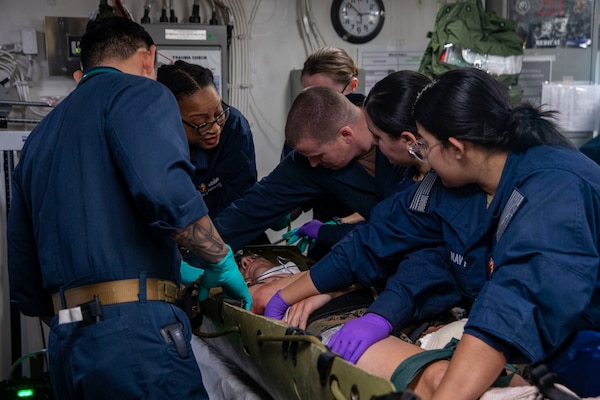 250205-N-QR506-1096 PHILIPPINE SEA (Feb. 5, 2025) Sailors assigned to the forward-deployed amphibious assault ship USS America (LHA 6) and Fleet Surgical Team (FST) 7, prepare to assess a simulated casualty in the ship’s medical bay during a mass casualty drill in the Philippine Sea, Feb. 5. America, lead ship of the America Amphibious Ready Group, along with the 31st Marine Expeditionary Unit, are underway conducting routine operations in the U.S. 7th Fleet area of operations. U.S. 7th Fleet is the U.S. Navy’s largest forward-deployed numbered fleet, and routinely interacts and operates with allies and partners in preserving a free and open Indo-Pacific region (U.S. Navy photo by Mass Communication Specialist Seaman Jeadan Andre)