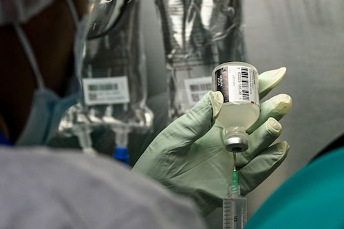 Syringe drawing fluid from bottle.