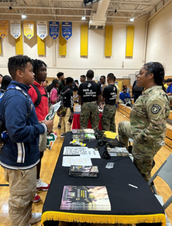 Female U.S. Army Recruiter discusses Army opportunities with high school students at a school tabling event