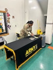 Female U.S. Army Recruiter in uniform sets up for tabling event