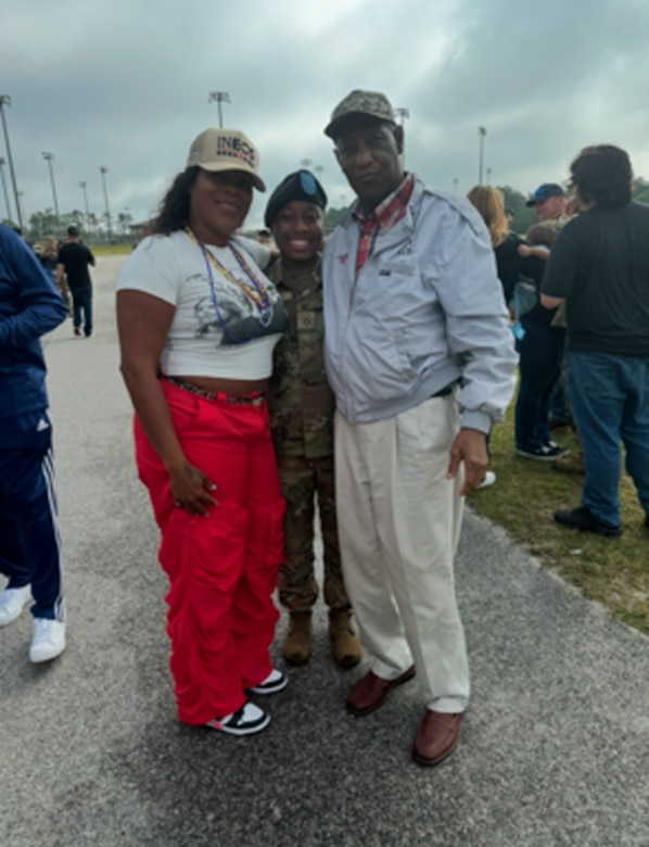 Mother and grandfather in civilian clothes poses with SPC Miracle Mattox who is in uniform