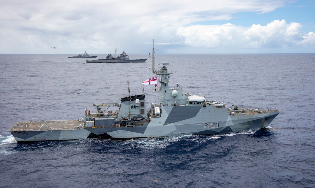 United Kingdom Royal Navy River-class offshore patrol vessel HMS Medway (P 223) steams alongside Ticonderoga-class guided-missile cruiser USS Normandy (CG 60) and Arleigh Burke-class guided-missile destroyer USS Thomas Hudner (DDG 116) as a NH-90 Neptune helicopter assigned to Royal Netherlands Navy Holland-class offshore patrol vessel HNLMS Groningen (P843) flies in the distance while conducting trilateral operations in the Caribbean Sea, March 3, 2025. USS Normandy  and USS Thomas Hudner are scheduled to protect U.S. interests in the region and strengthen maritime partnerships through bilateral, trilateral, and multinational maritime operations and Theater Security Cooperation (TSC) port visits. U.S. Naval Forces Southern Command/U.S. 4th Fleet is the maritime component of U.S. Southern Command and the trusted maritime partner for Caribbean, Central, and South American maritime forces leading to improved unity, security, and stability. (U.S. Navy photo by Mass Communication Specialist 2nd Class Dylan M. Kinee/Released)