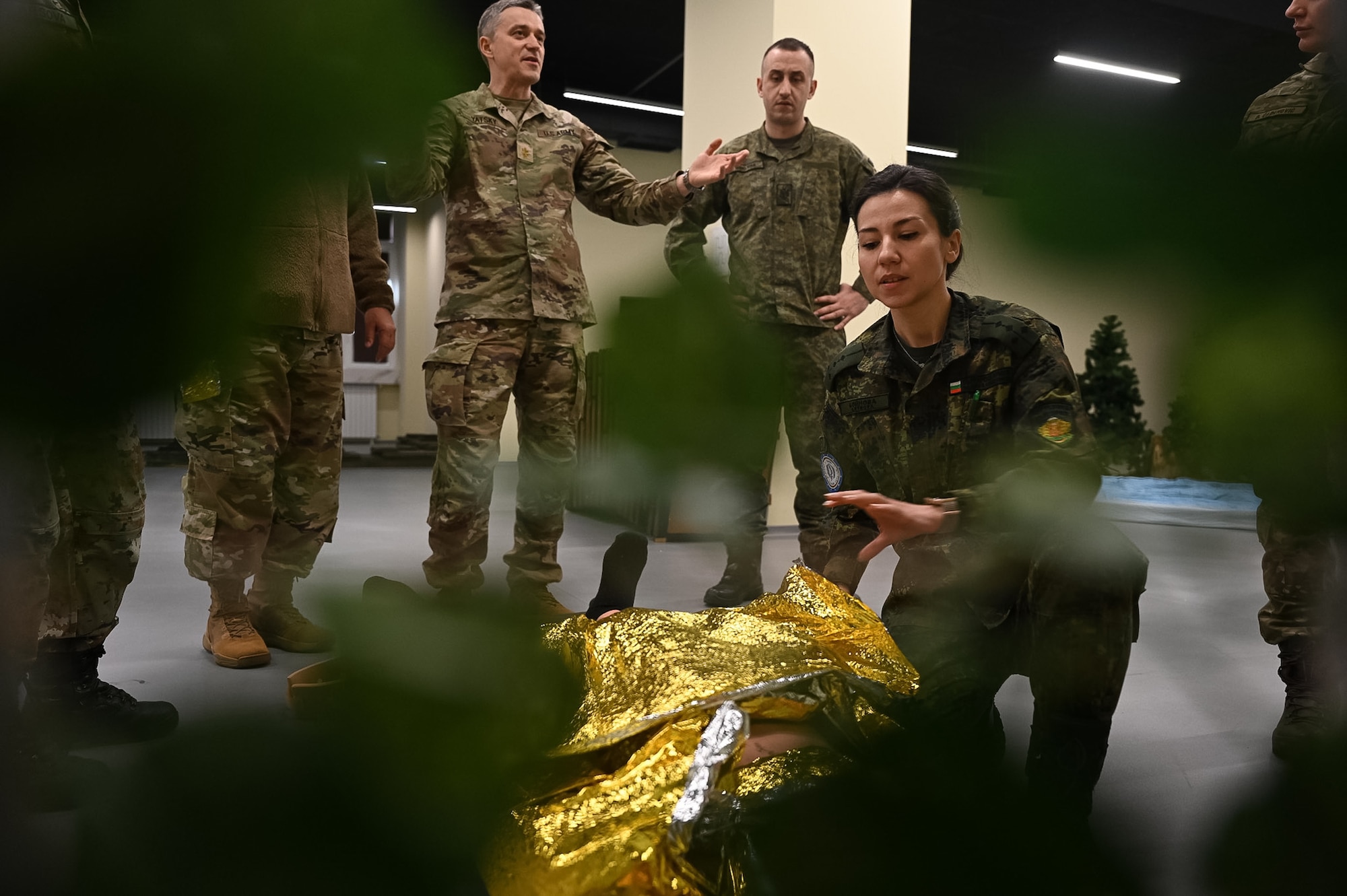 instructors from the U.S. and Bulgaria explain how to wrap a foil blanket around wounded military personnel