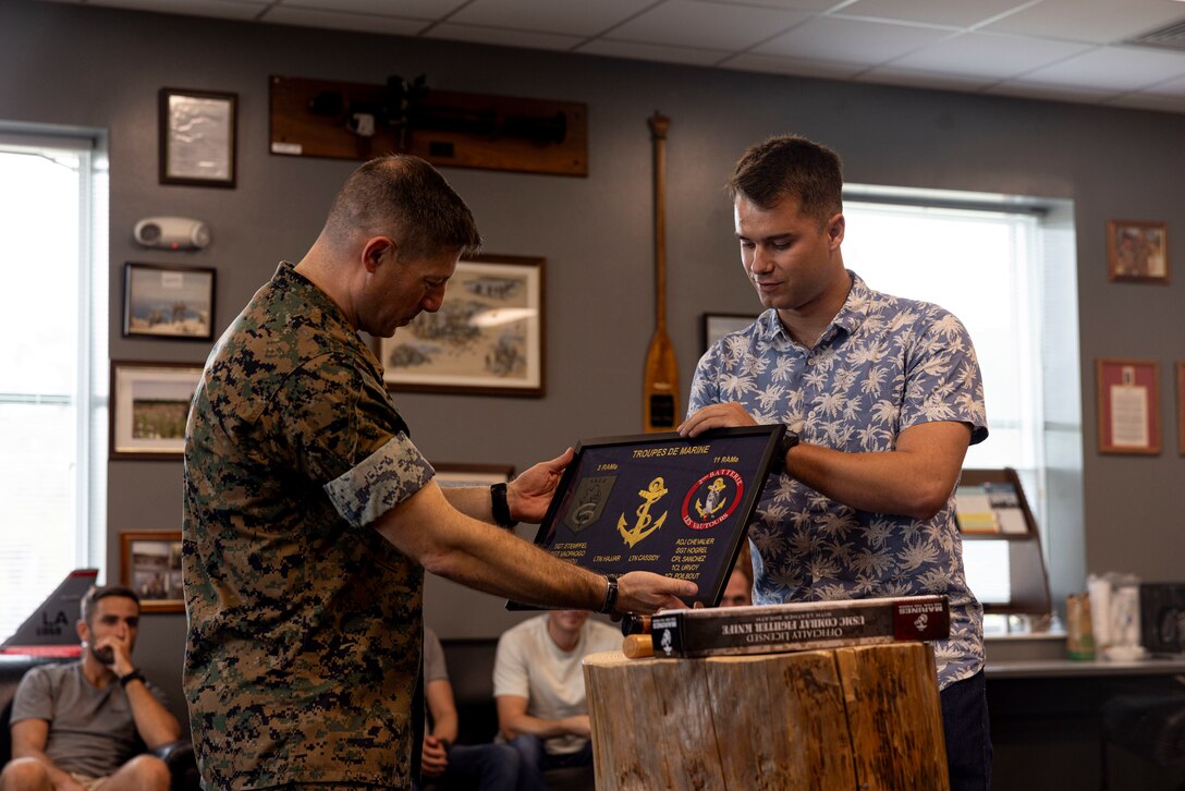 U.S. Marine Corps Lt. Col Daniel Kovatch, the commanding officer of 2nd Air Naval Gunfire Liaison Company, II Marine Expeditionary Force Information Group, and NATO Allied service members perform a gift exchange concluding Burmese Chase 24 at Marine Corps Base Camp Lejeune, North Carolina, Sept. 27, 2024. Burmese Chase is an annual U.S. led, multilateral exercise that includes training on integration of ground and air fires, infantry tactics and naval gunfire alongside NATO allies and partners. (U.S. Marine Corps Photo by Lance Cpl. Kenya J Bolton)