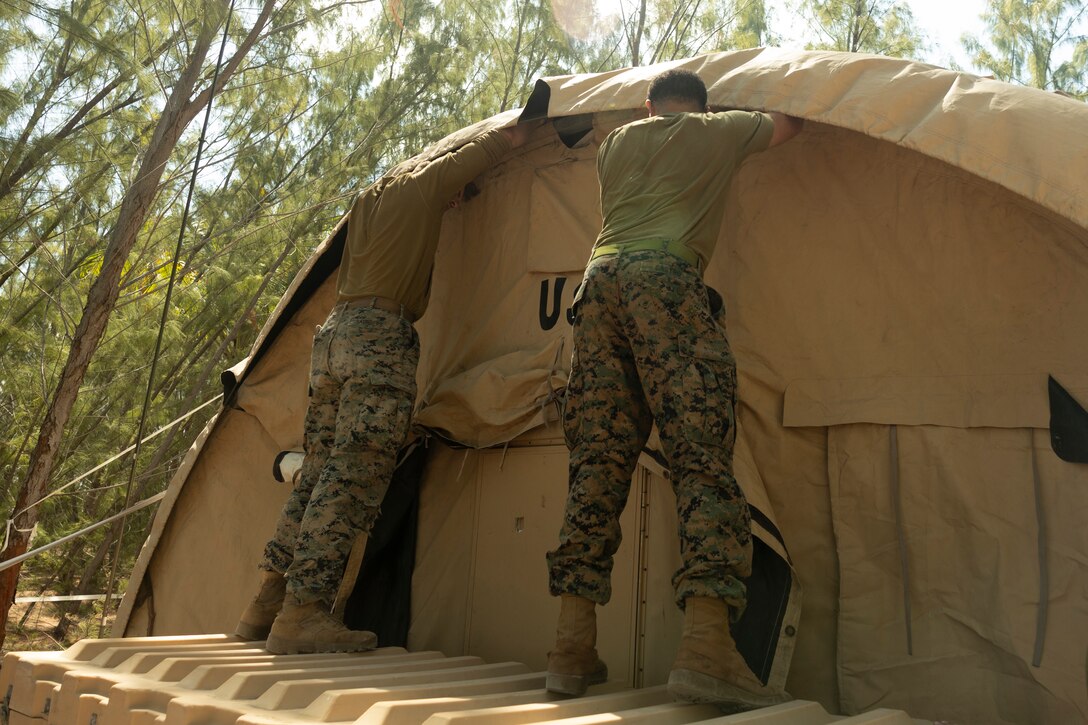 U.S. Marine Corps Cpl. Edward Saunders, left, from Montana, a radio operator with Marine Wing Communications Squadron 28, and Cpl. Amaury Castro, from New York, a ground electronic transmission system maintainer with 2nd Low Altitude Air Defense Battalion, repair a tent near the U.S. Navy's Atlantic Undersea Test and Evaluation Center on Andros Island, Bahamas, Feb. 22, 2025. 2nd Marine Aircraft Wing units deployed to the Bahamas to conduct aviation ground support rehearsals and refine distributed aviation operations. (U.S. Marine Corps photo by Lance Cpl. Mya Seymour)
