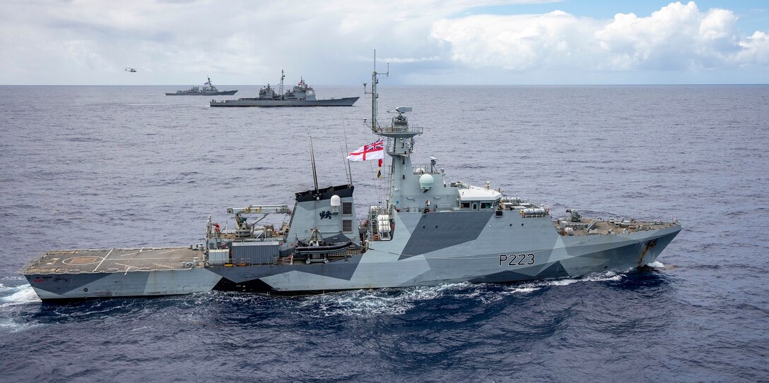 Three navy warships sailing alongside each other at sea.