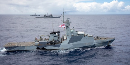 Three navy warships sailing alongside each other at sea.