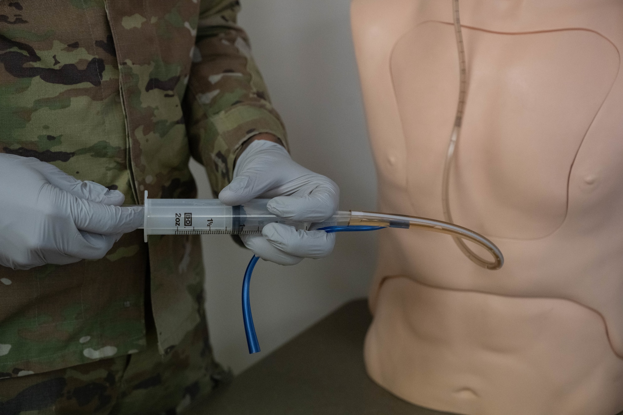 An Airman practices using a feeding tube on a medical mannequin.