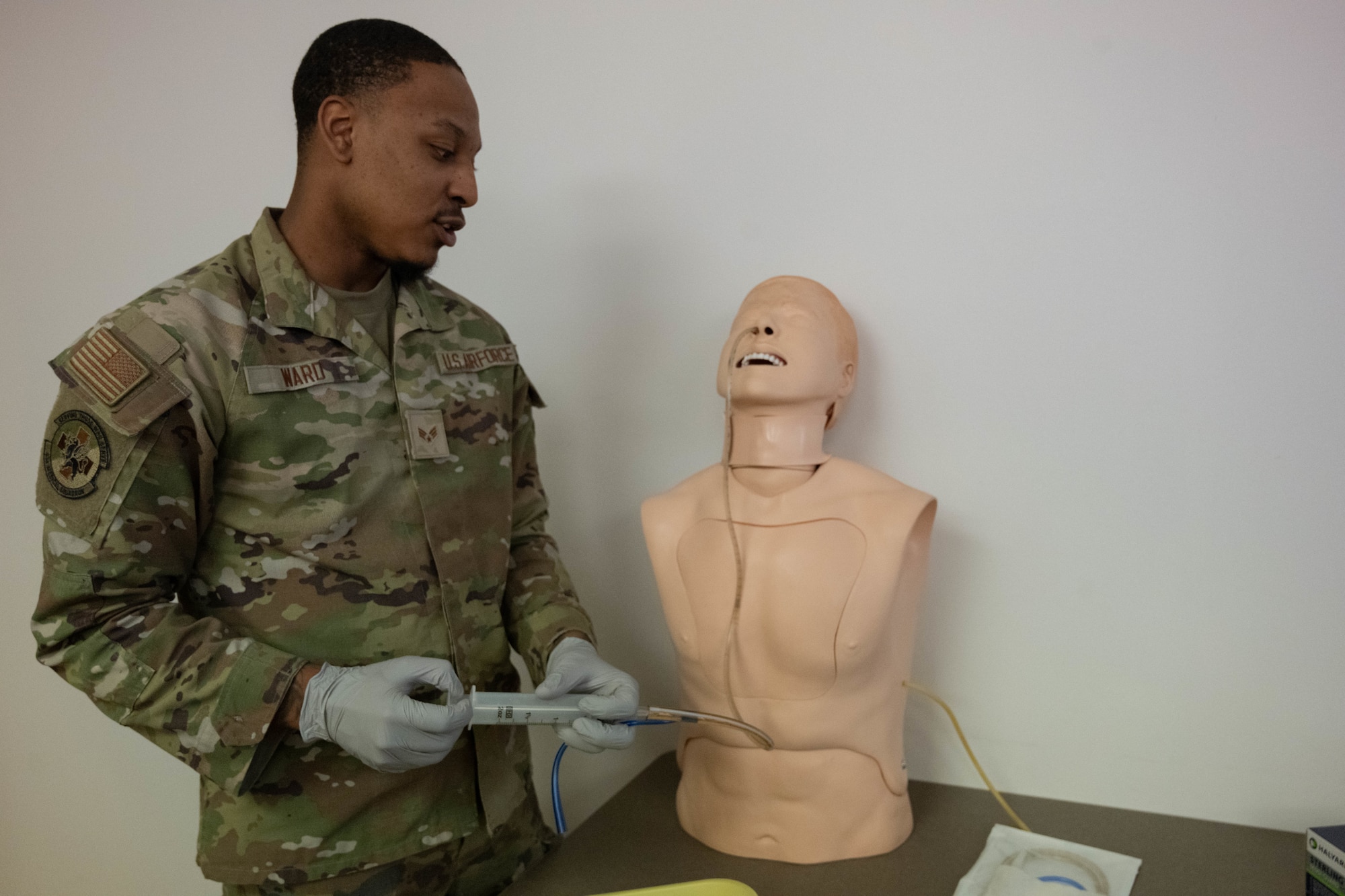 An Airman practices using a feeding tube on a medical mannequin.