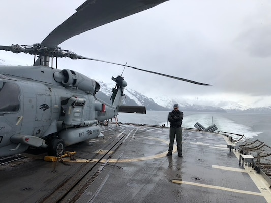 FALLON, NV.–  U.S. Navy Lt. John Hartsough poses with an MH-60 helicopter during a training exercise. Hartsough is a helicopter pilot in the SEAHUNTER portion of warfare/weapons tactics instruction and is enrolled in the new Masters of Warfare Operations (MWO) degree program at the Naval Postgraduate School. The Naval Aviation Warfighting Development Center (NAWDC) hosts a range of naval aircraft for training in all mission areas including the MH-60 helicopter. (U.S. Navy photo courtesy of Lt. Hartsough.)