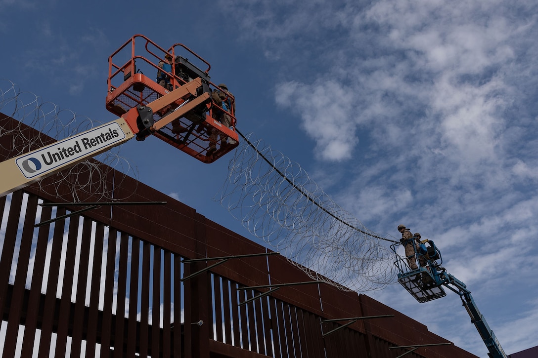 Marine use a lift to put wire on a fence.