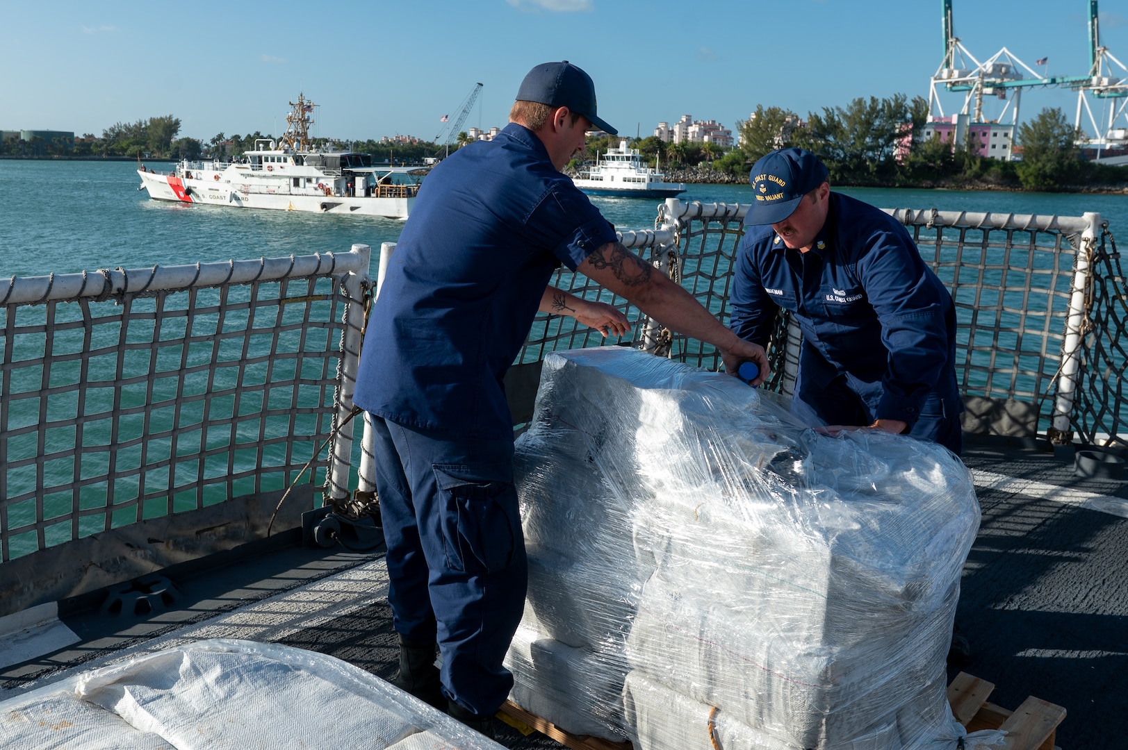 Crew members from USCGC Valiant (WMEC 621) using plastic wrap to bind interdicted narcotics at Base Miami Beach, Florida, Mar. 6, 2025. The Valiant's crew secured the illegal drugs after six interdictions in the international waters of the Caribbean. (U.S. Coast Guard photo by Petty Officer 3rd Class Nicholas Strasburg)