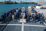 Crew members from USCGC Valiant (WMEC 621) stand at parade rest in front of interdicted narcotics at Base Miami Beach, Florida, Mar. 6, 2025. The Valiant's crew secured the illegal drugs from six interdictions in the international waters of the Caribbean. (U.S. Coast Guard photo by Petty Officer 3rd Class Nicholas Strasburg)