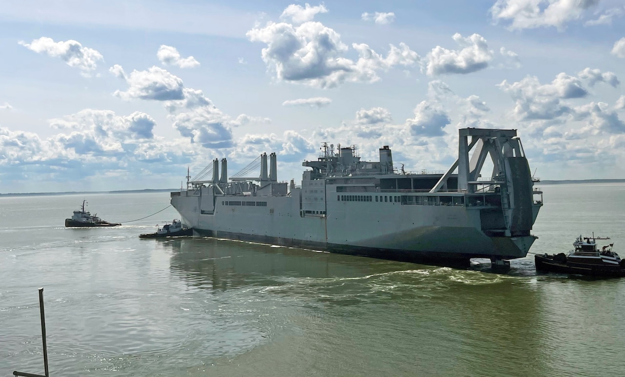 A large ship is pulled through water by a smaller ship.