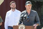 Two men stand near a lectern.