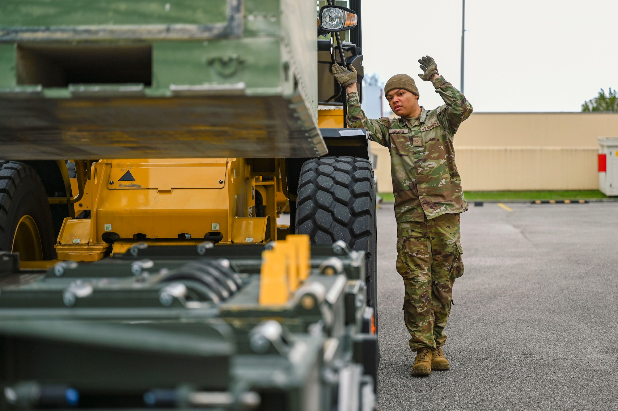 Airman 1st Class Zechariah Brannon walks alongside a forklift directing it