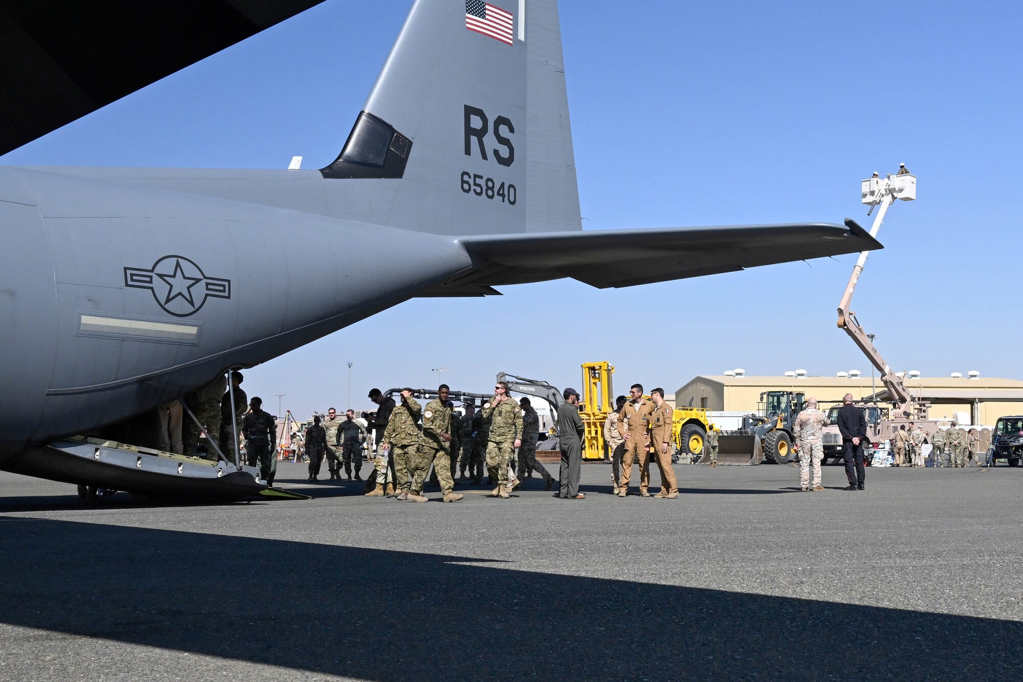 People in uniform conversate behind an aircraft.