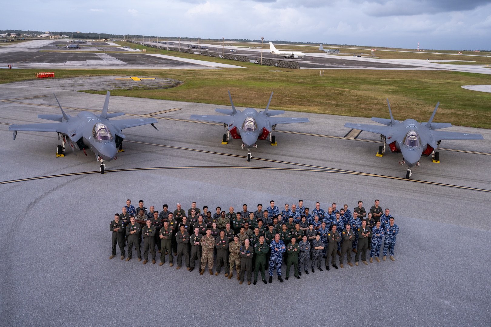 Allies from the United States, Japan and Australia come together on the flightline in front of three F-35A Lightning IIs to celebrate the end of exercise Cope North 2025 at Andersen Air Force Base, Guam, Feb. 21, 2025.