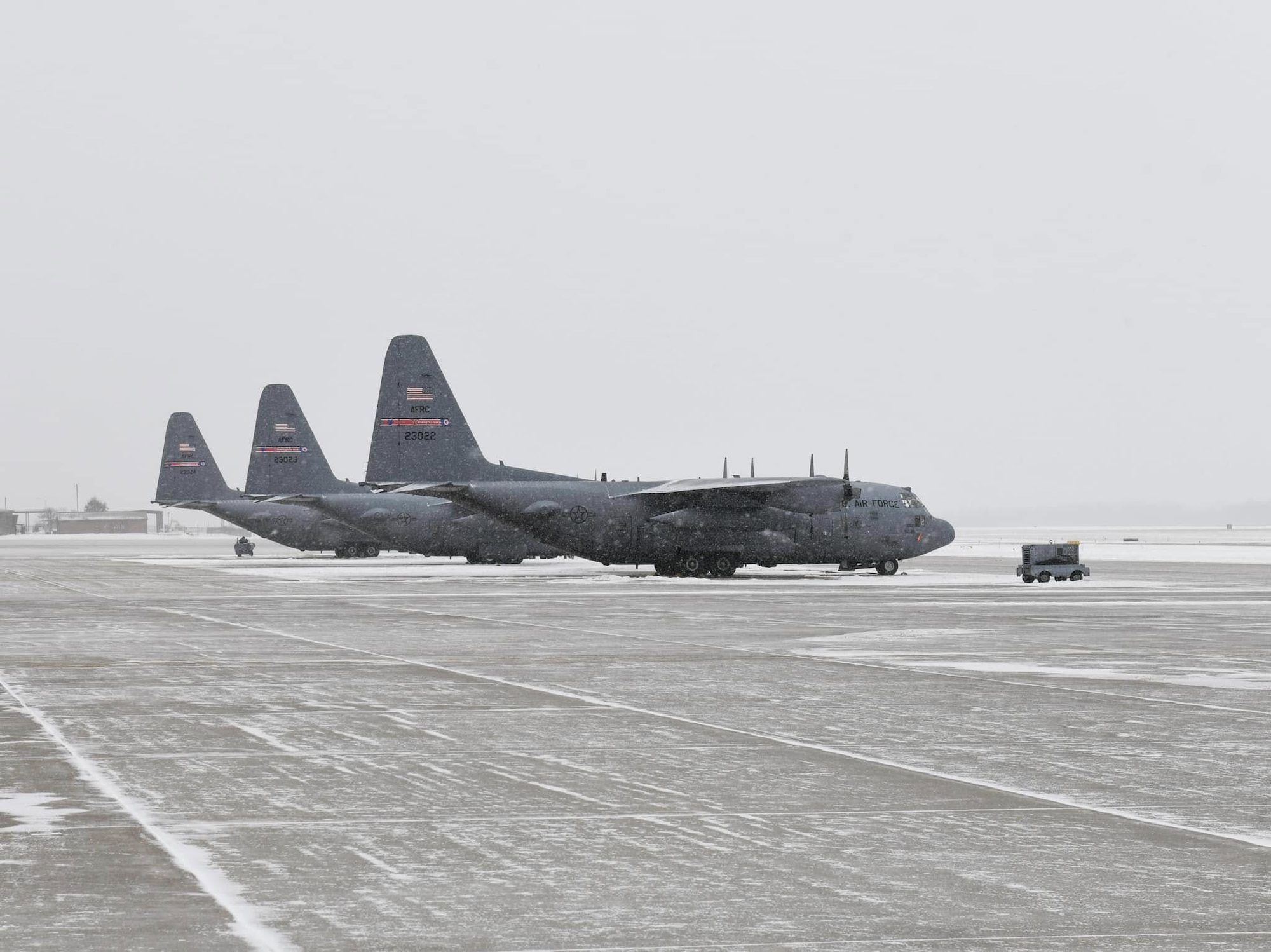 A row of C-130 aircraft assigned to the 910th Airlift Wing sit on the flightline at Youngstown Air Reserve Station, Ohio, on a cold winter day.