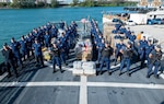 Crew members from USCGC Valiant (WMEC 621) stand at parade rest in front of interdicted narcotics at Base Miami Beach, Florida, Mar. 6, 2025. The Valiant's crew secured the illegal drugs from six interdictions in the international waters of the Caribbean. (U.S. Coast Guard photo by Petty Officer 3rd Class Nicholas Strasburg)