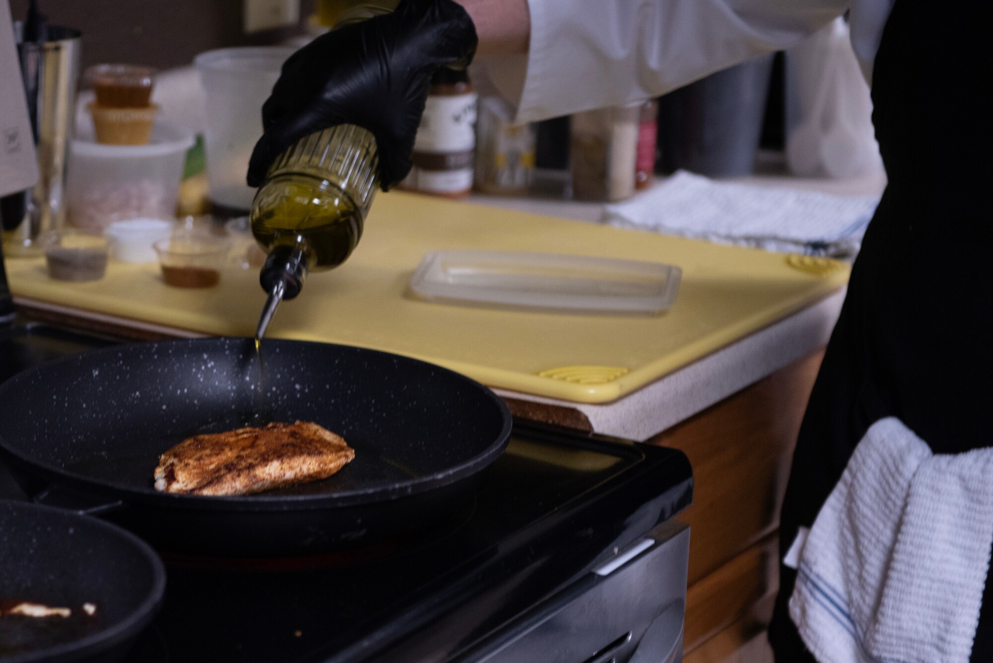 A U.S. Air Force enlisted aide assigned to Air Force Special Operations Command pours olive oil into a pan during a Cooking with Command event at Hurlburt Field, Florida, Feb. 11, 2025.