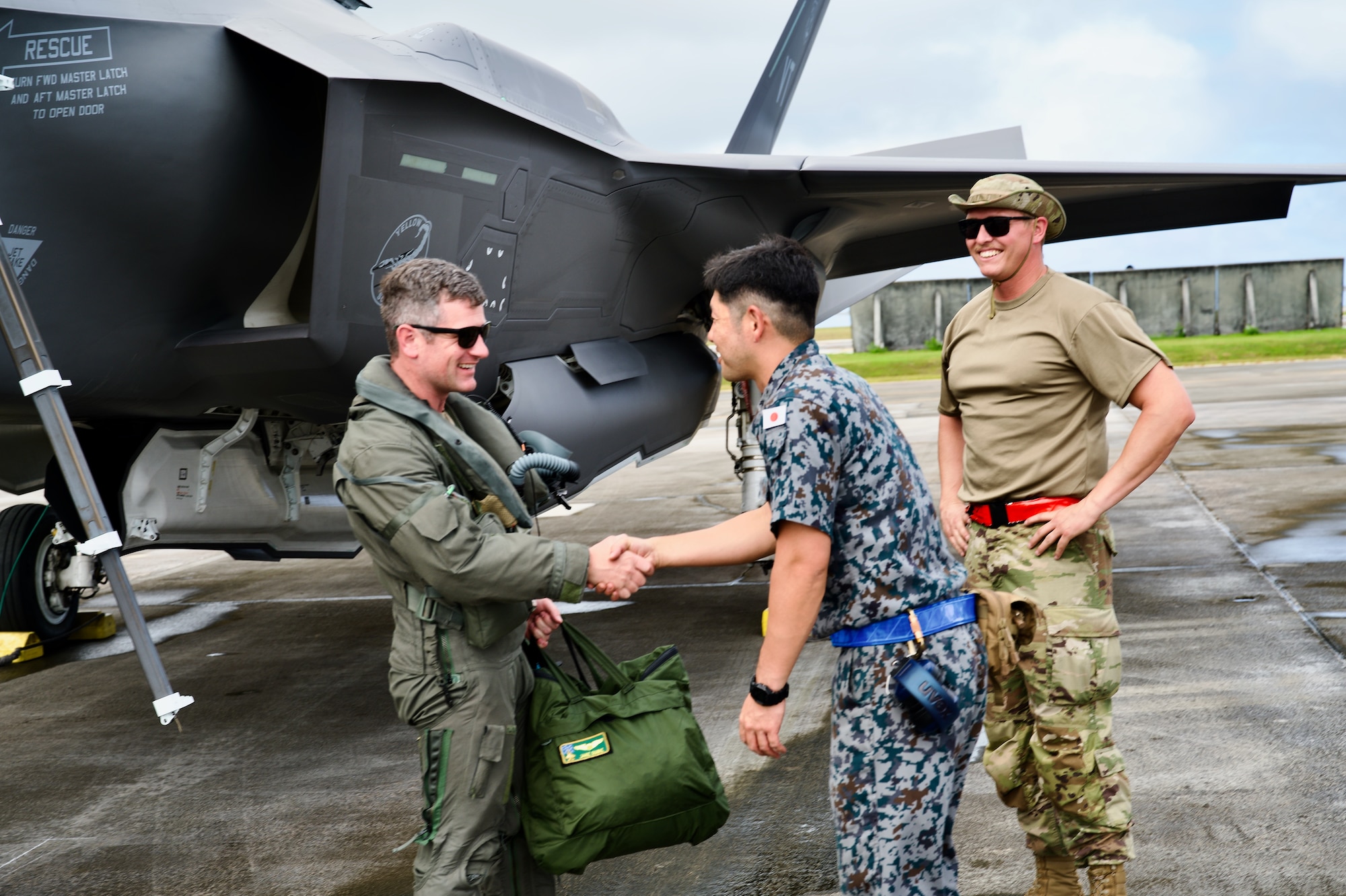 Photo of U.S. Air Force Maj. Jacob Dubie shaking hands with Japan Air Self-Defense Force Tech. Sgt. Shoi Semba while Tech. Sgt. Mathew Couture looks on during Cope North 2025, Feb. 9, 2025. As part of cross-service integration, Japanese crew chiefs worked between flight rotations, honing communication with pilots and providing post-flight marshalling services.