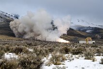 Fire and smoke from a static fire test are shown against a hillside