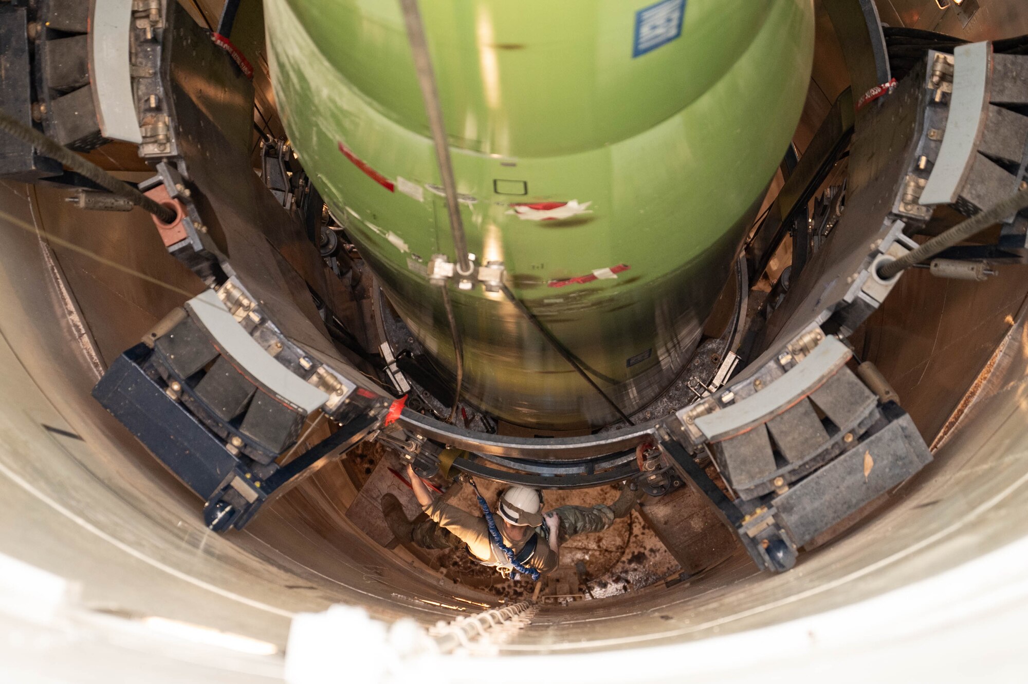 A man in uniform performs missile maintenance.