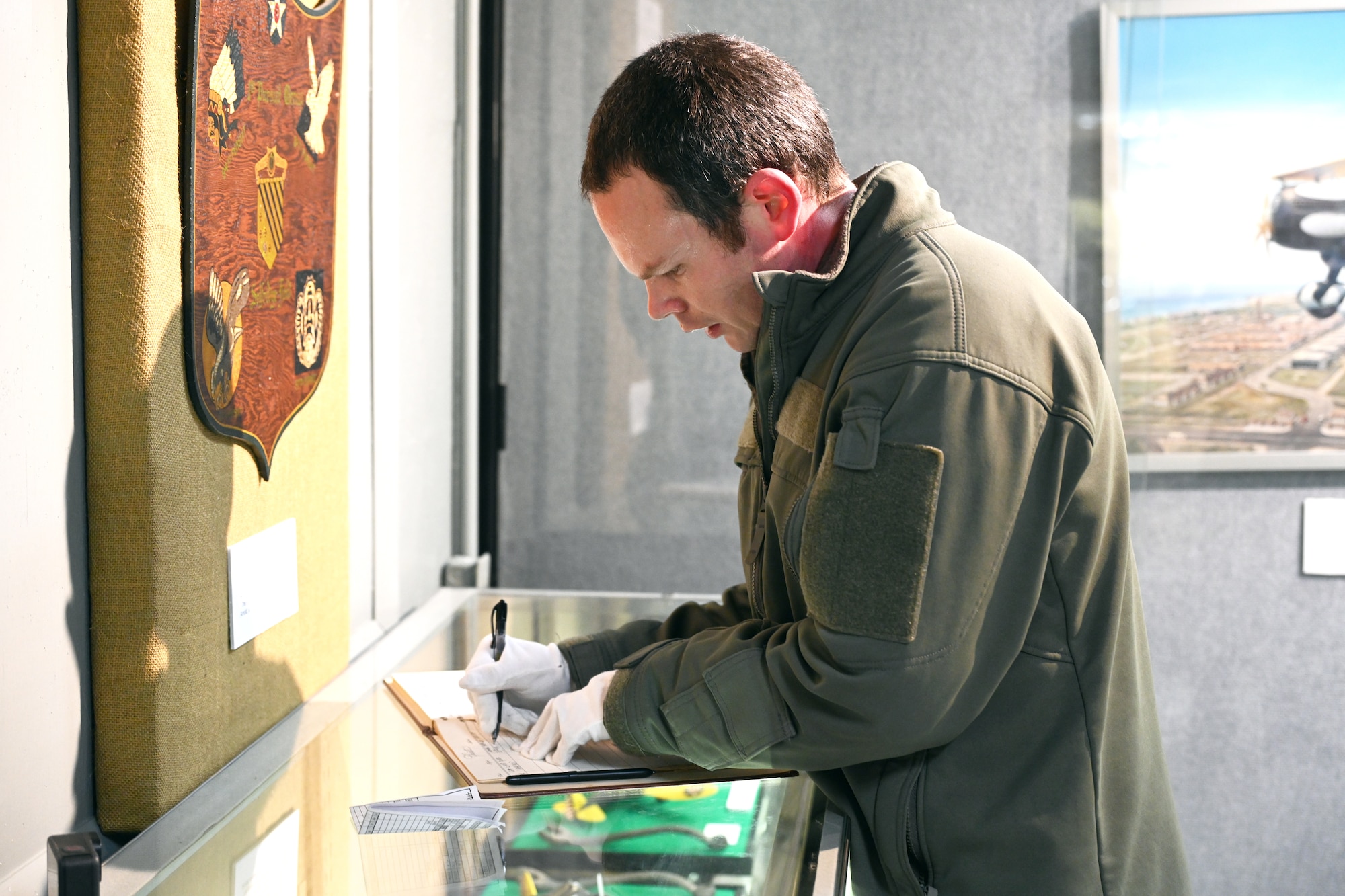 Male pilot signing a book on a glass display.