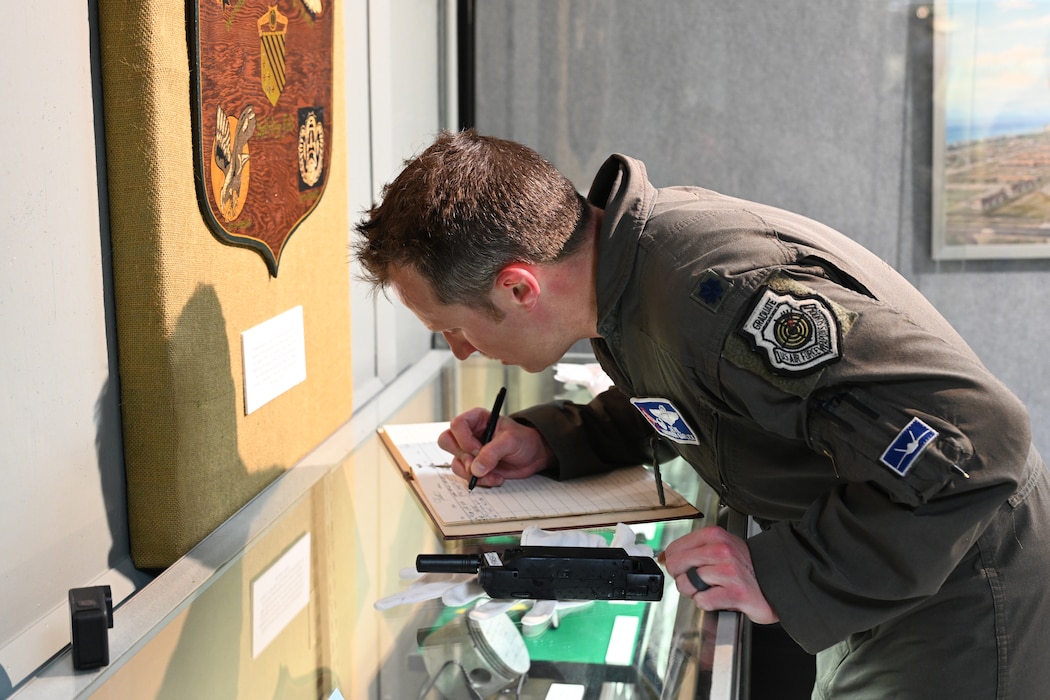 Male pilot signing a book on a glass display.