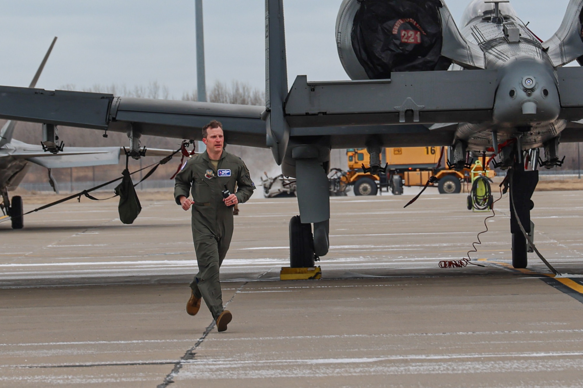 Male pilot in flight suit running in front of an A-10 Thunderbolt II attack jet.