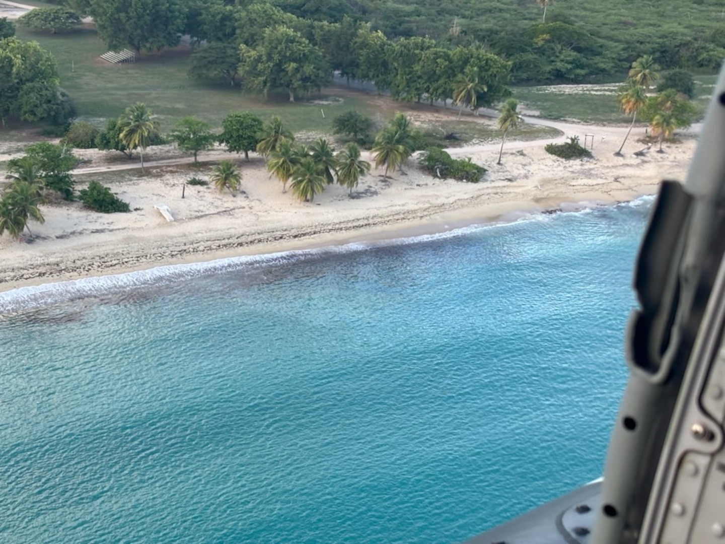 A Coast Guard Air Station Borinquen MH-60T Jayhawk helicopter crew, with Coast Guard Sector San Juan environmental response investigator onboard, conduct and overflight assessment of a mystery sheen on the Sun Bay Beach shoreline in Vieques, March 7, 2025. As the investigation and response efforts continue, the Coast Guard urges any beachgoers to stay out of the water and follow directions from local emergency response personnel on scene. (U.S. Coast Guard photo)