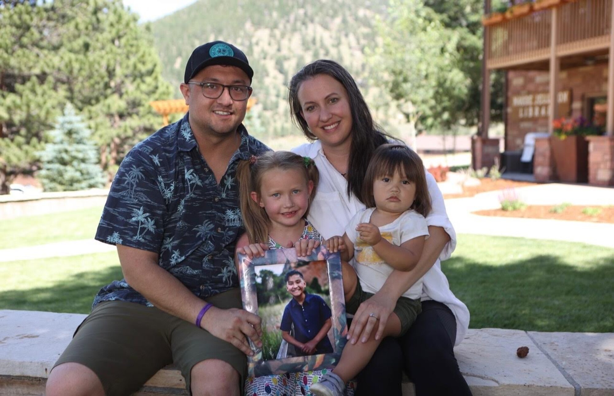 U.S. Air Force Master Sgt. Ryan McConnell, 42nd Force Support Squadron Airman Leadership School commandant, and his spouse, Tech. Sgt. Kathleen McConnell, Force Support Professional Development School master resilience trainer course instructor, pose for a photograph with their two daughters, Adelaide Keawe McConnell, left, and Effie Narumi McConnell, right, while holding a picture of Levi Kekoa McConnell in Colorado, March 7, 2022.