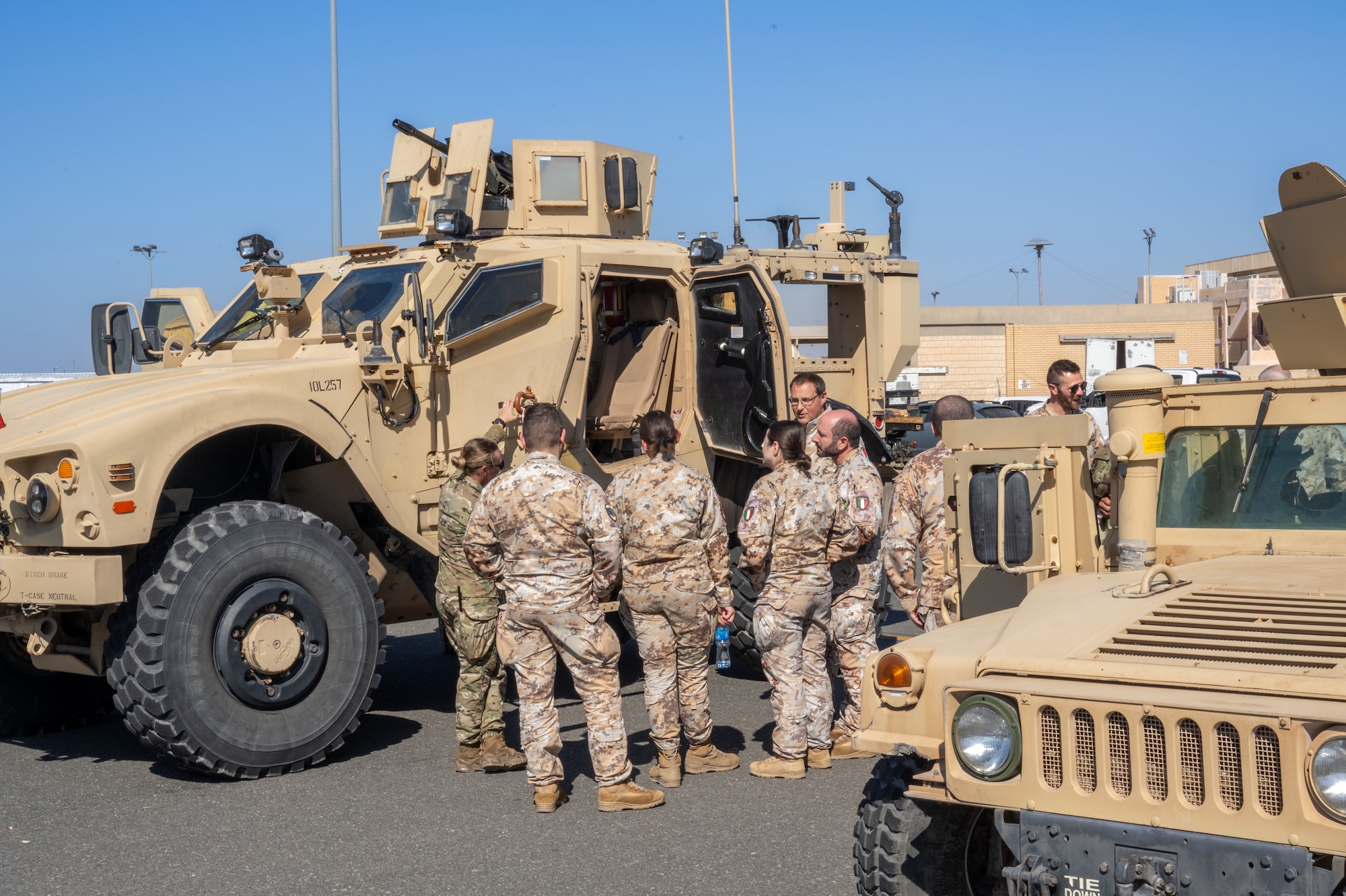 U.S. and Italian service members in uniform interact in front of a vehicle during an air expo.