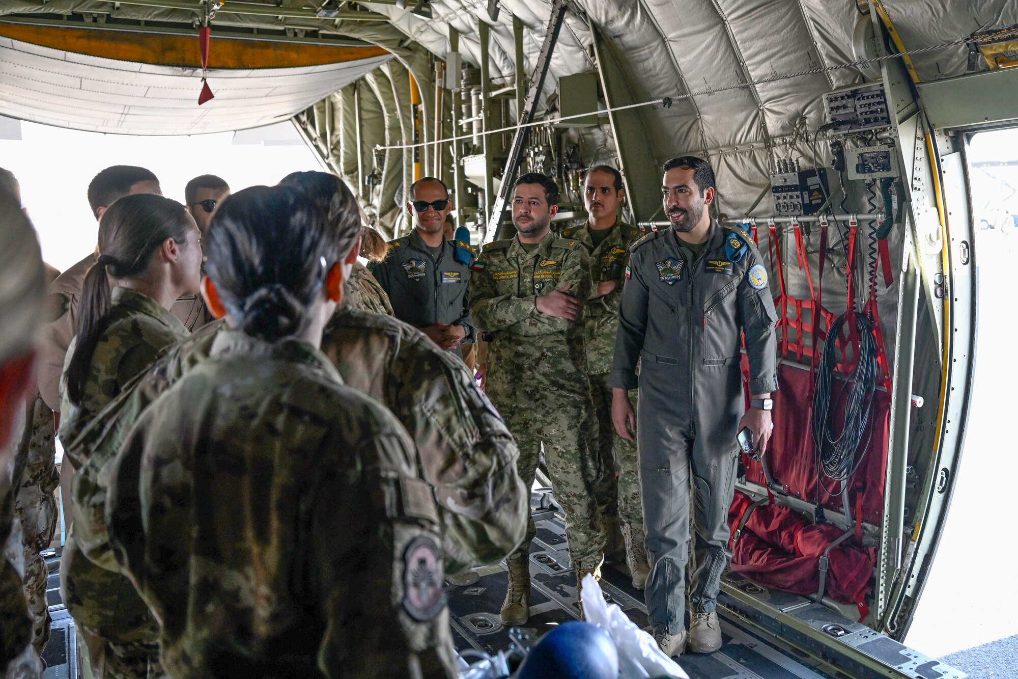 People in uniform walk through the inside of an aircraft.