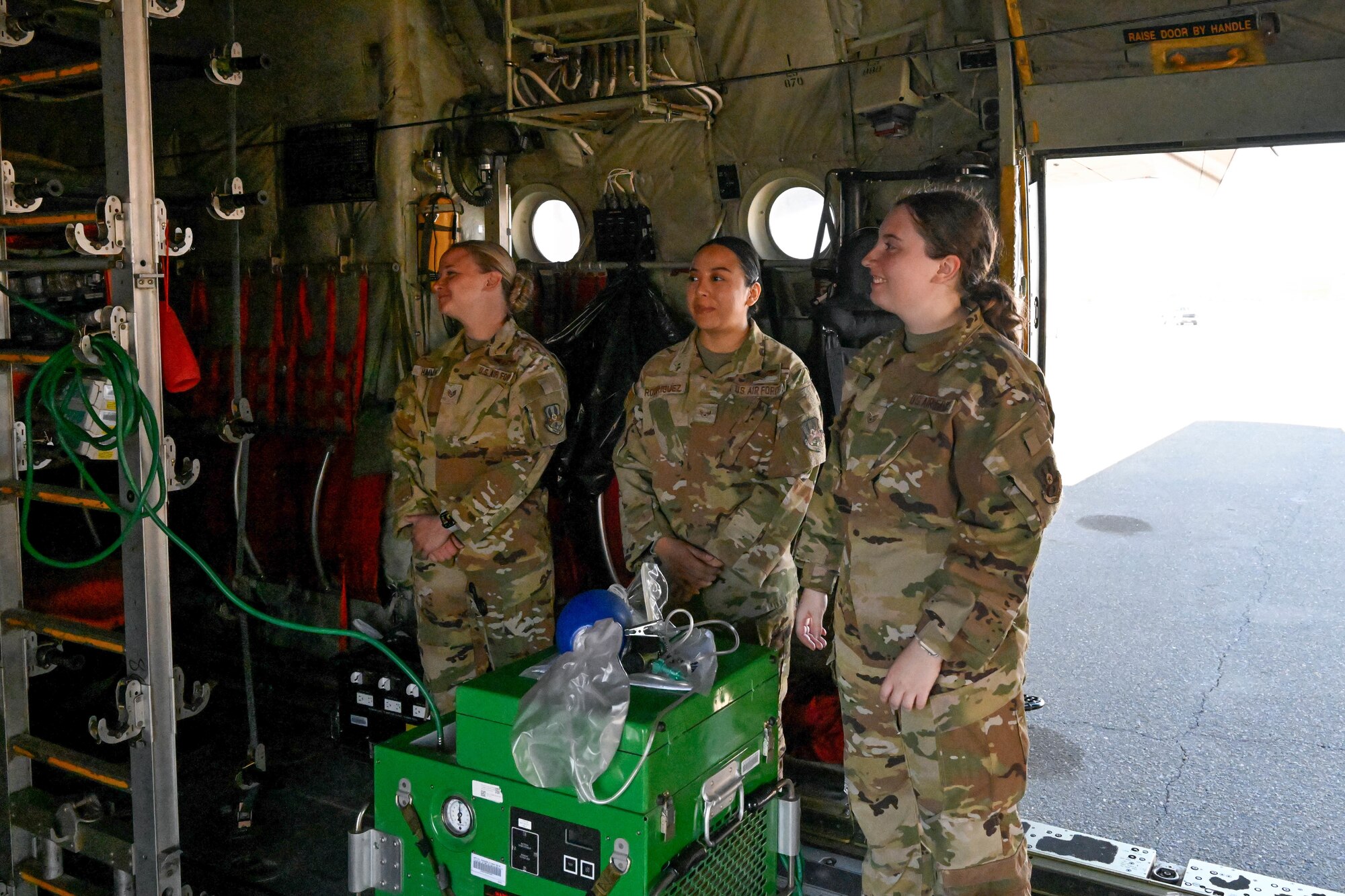 Women in uniform stand in an aircraft.