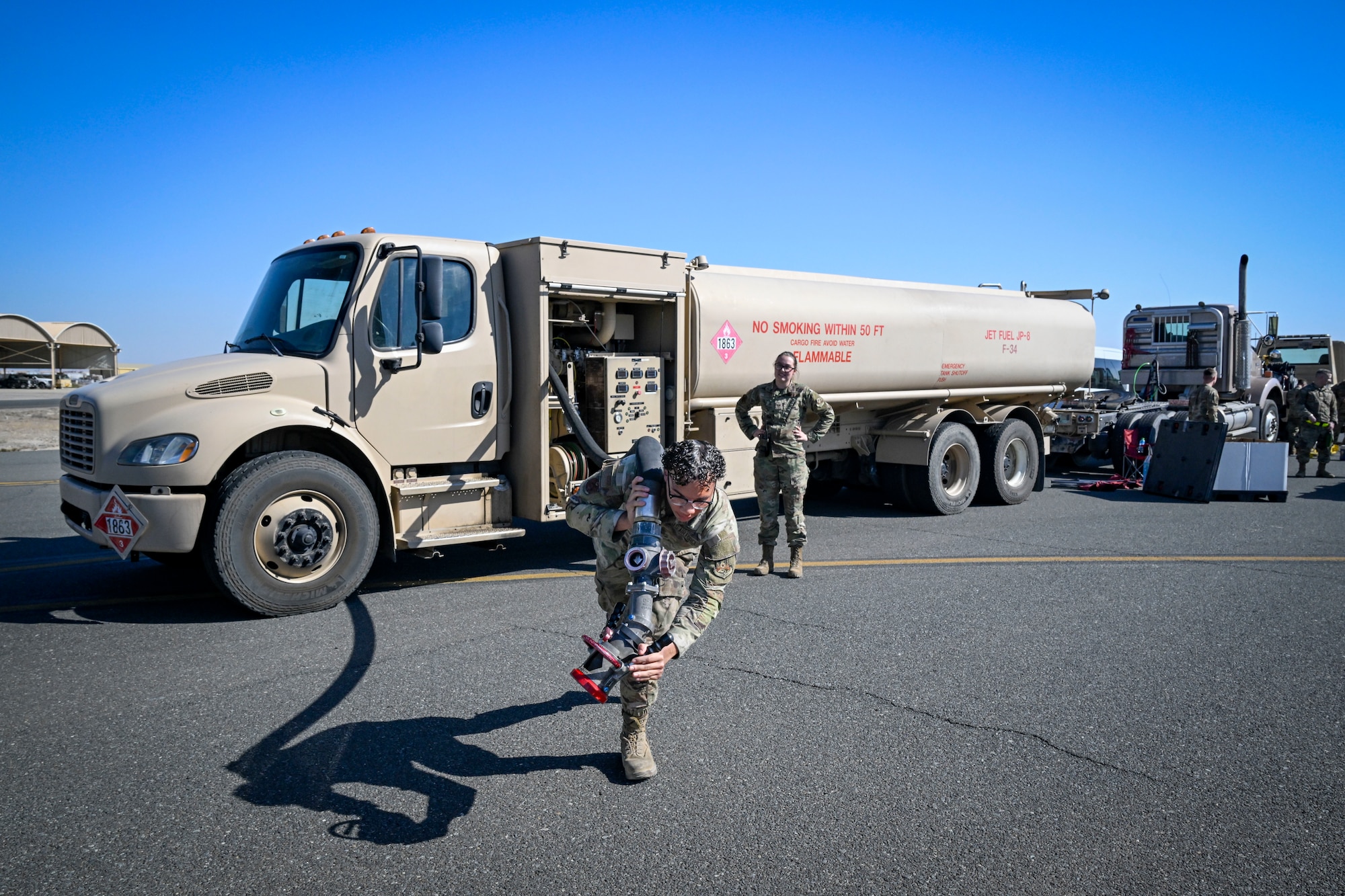 A man in uniform carries a hose from a truck.