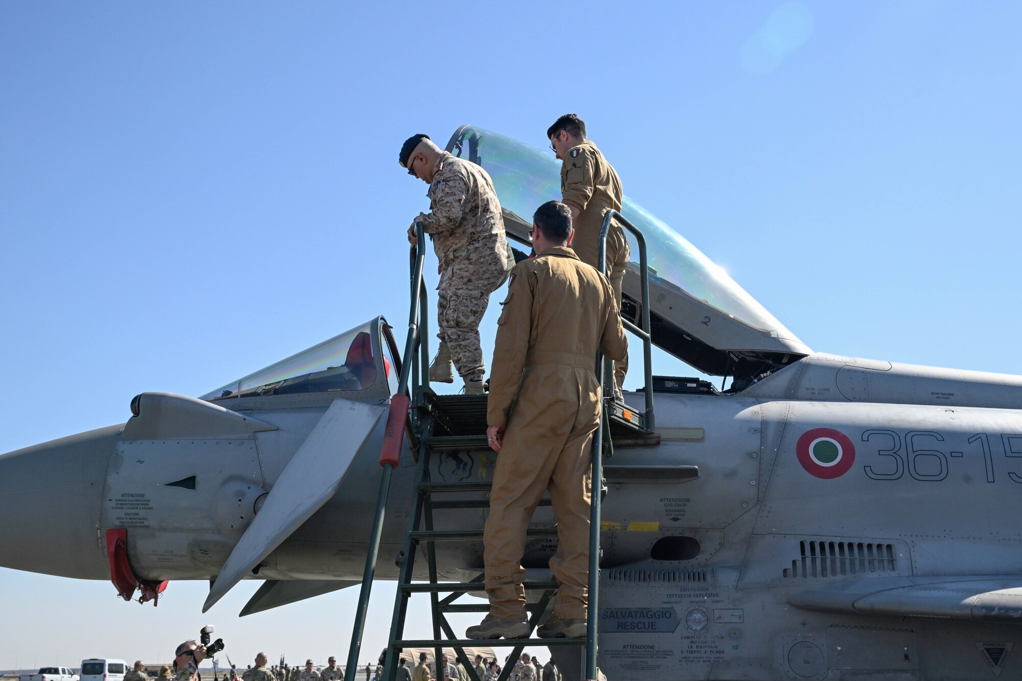 People in uniform climb onto a fighter jet.