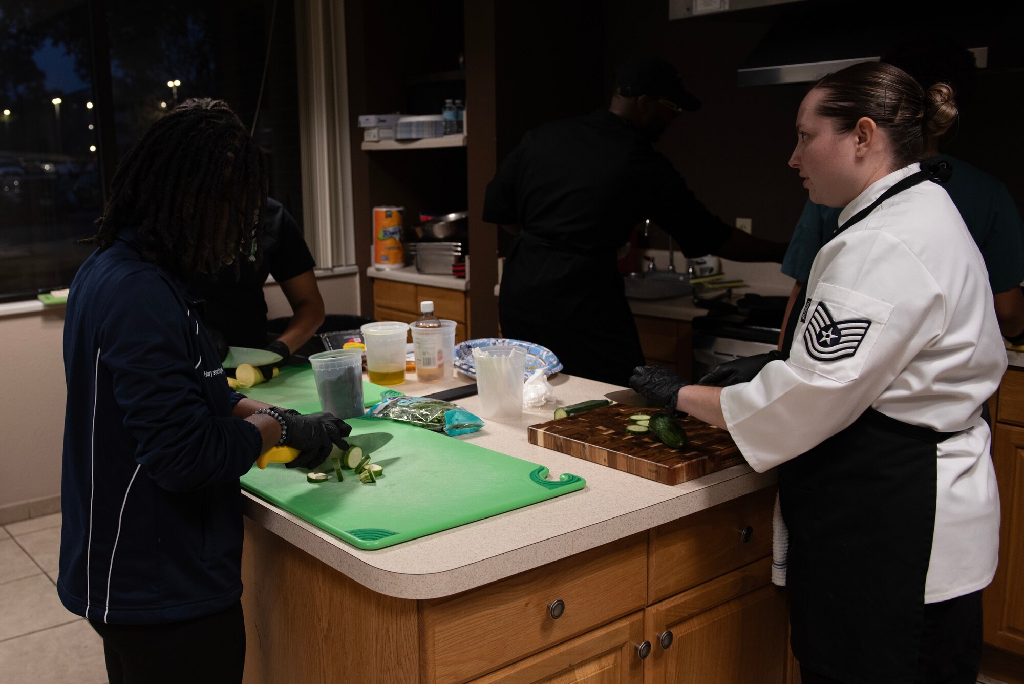 A U.S. Air Force enlisted aide (right), assigned to Air Force Special Operations Command, demonstrates to Airmen how to properly cut vegetables at Hurlburt Field, Florida, Feb. 11, 2025.