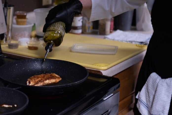 A U.S. Air Force enlisted aide assigned to Air Force Special Operations Command pours olive oil into a pan during a Cooking with Command event at Hurlburt Field, Florida, Feb. 11, 2025.